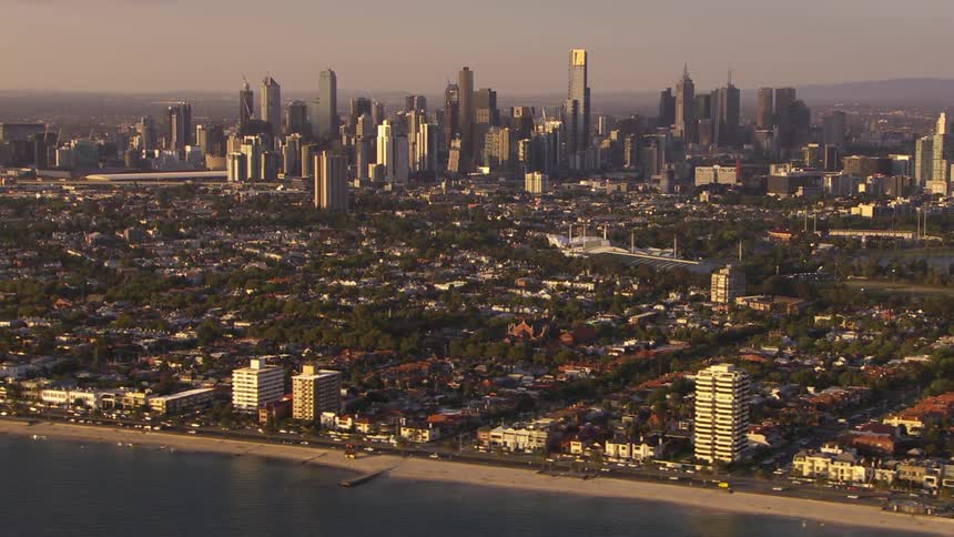 A city skyline behind the ocean at sunset