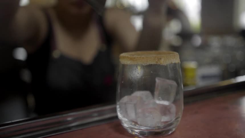 A woman puts ice into a small glass