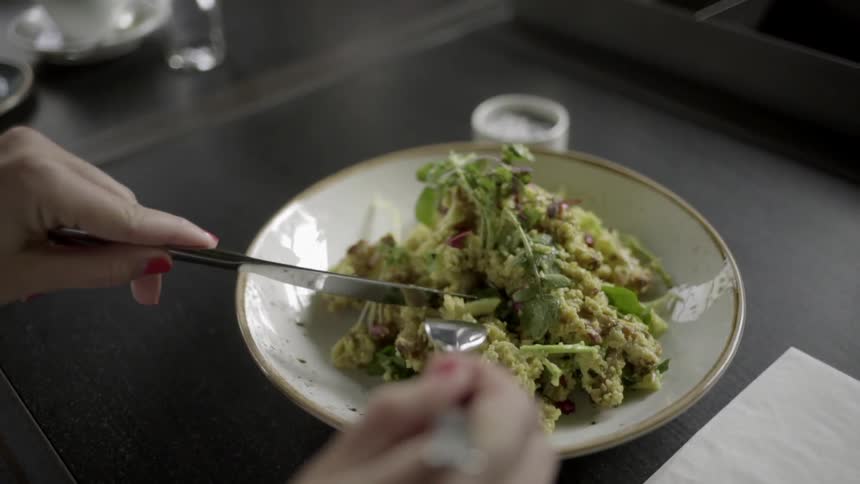 Woman using utensils to eat a salad