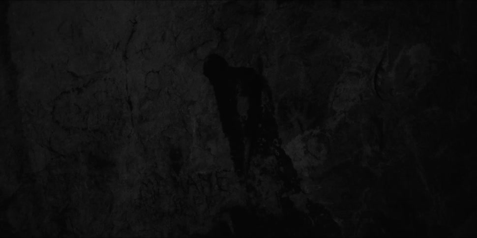 A shadow of a man is barely visible on dark gray rocks