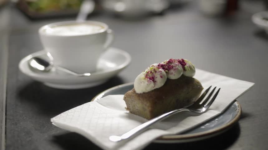 Coffee being placed next to a frosted pastry