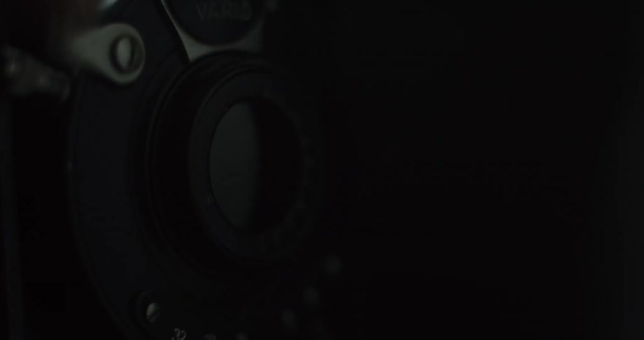 A photographer pushes a lever down to take pictures with a vintage camera