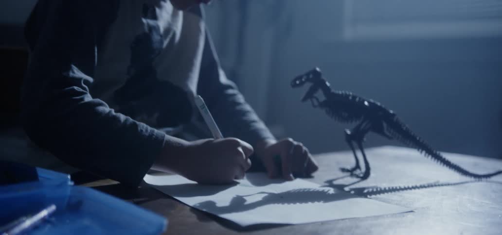 A young boy writes on a piece of a paper