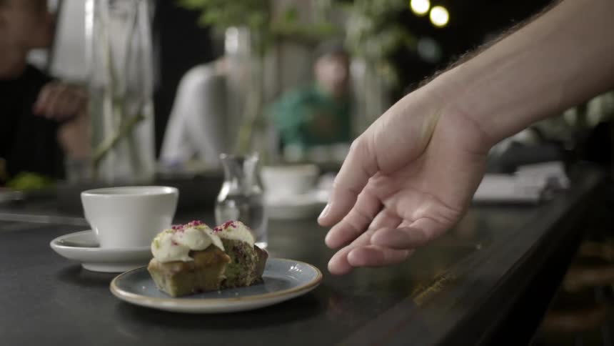A woman setting a dessert plate on a table next to a coffee