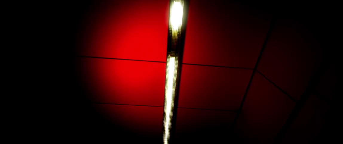 The light is on the ceiling of the dark hall