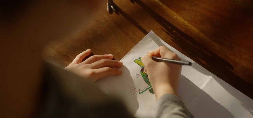 A child is coloring a dinosaur from his toy
