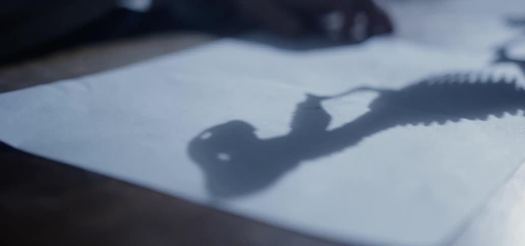 A shadow of a dinosaur skeleton sits on a piece of paper