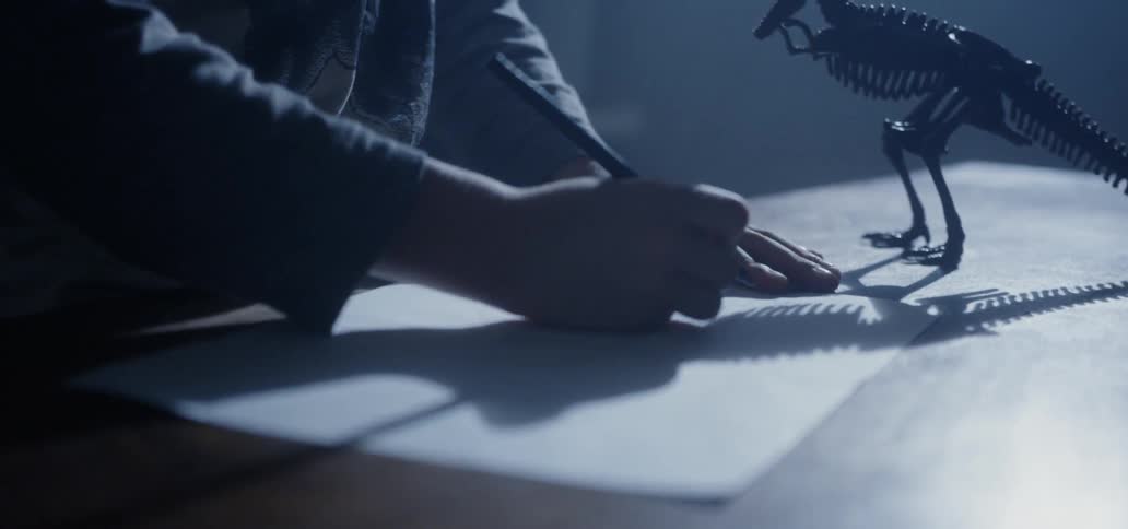 A child is drawing with his toy nearby