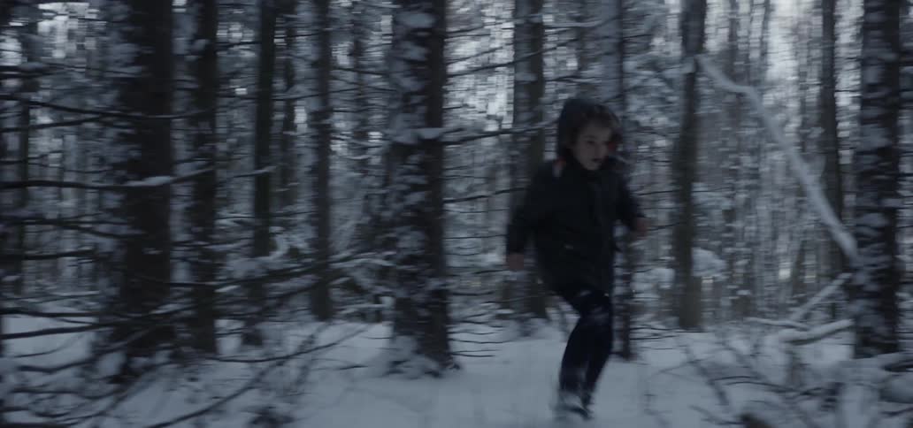 A child runs through a snowy forest