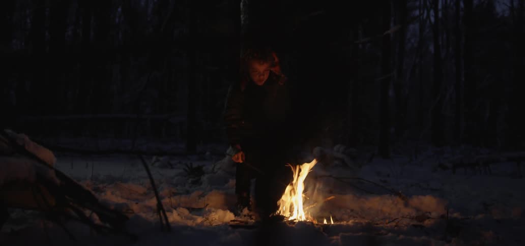 A young boy roasts a marshmallow over a campfire