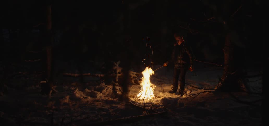 Child cooks food on skewer over open fire outdoors in the snow