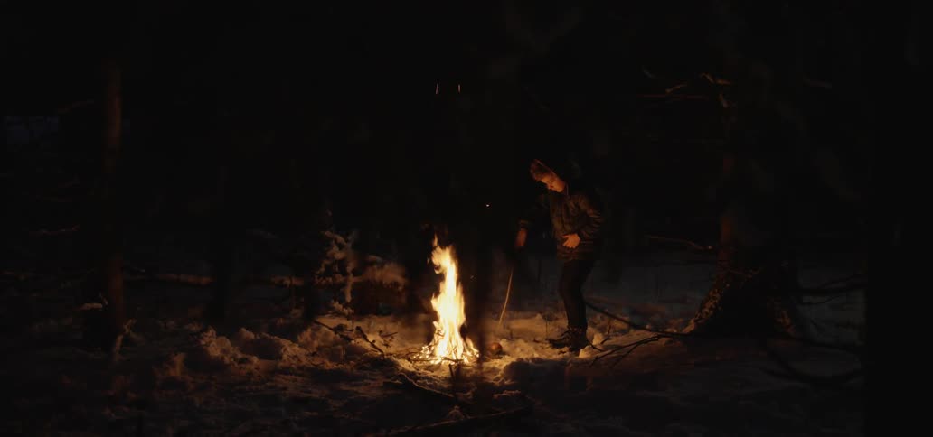A person stands next to a roaring fire