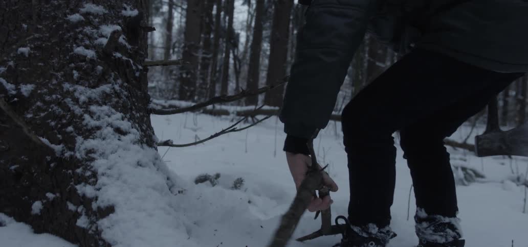 A person gathers sticks in a snowy forest