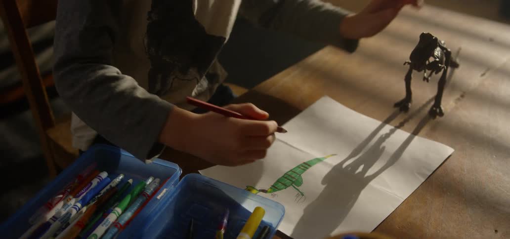 A child colors in a drawing of a dinosaur