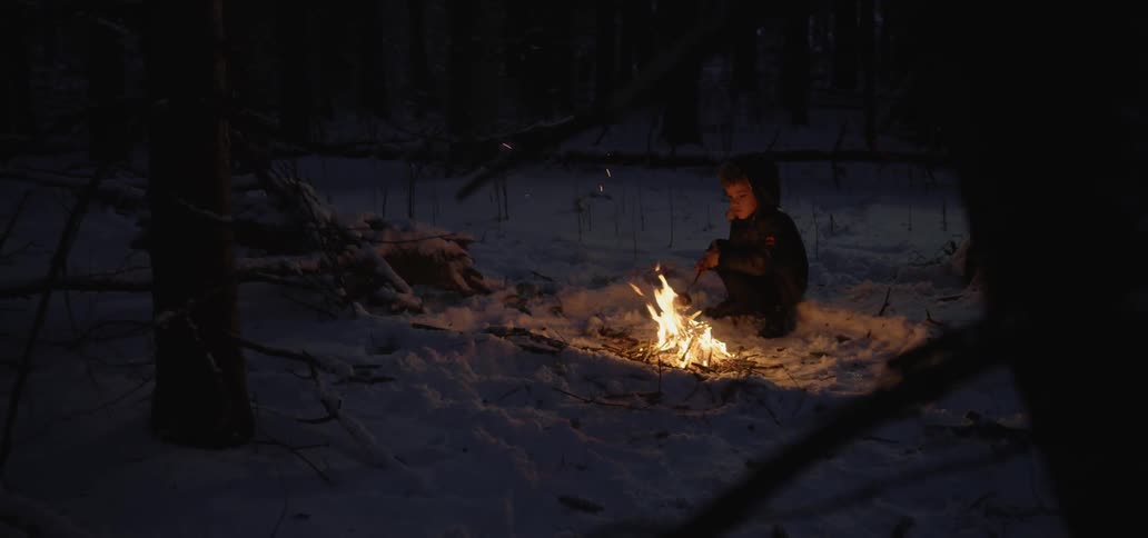 A woman sitting in the front of a campfire