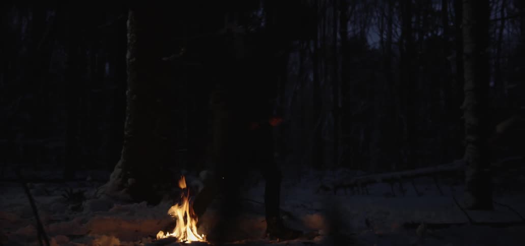 A person stands up and walks away from a camp fire