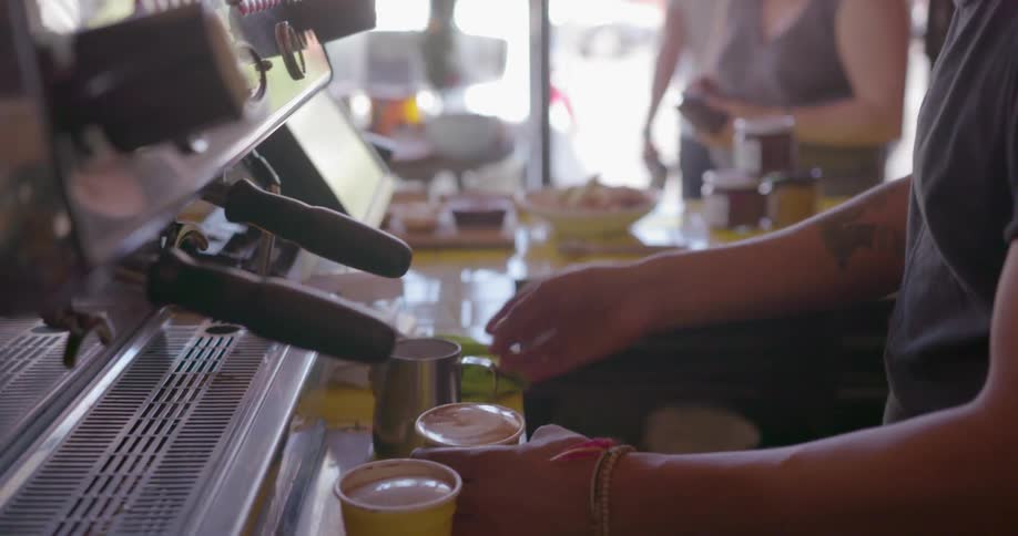 A woman is pouring a drink in a cafe
