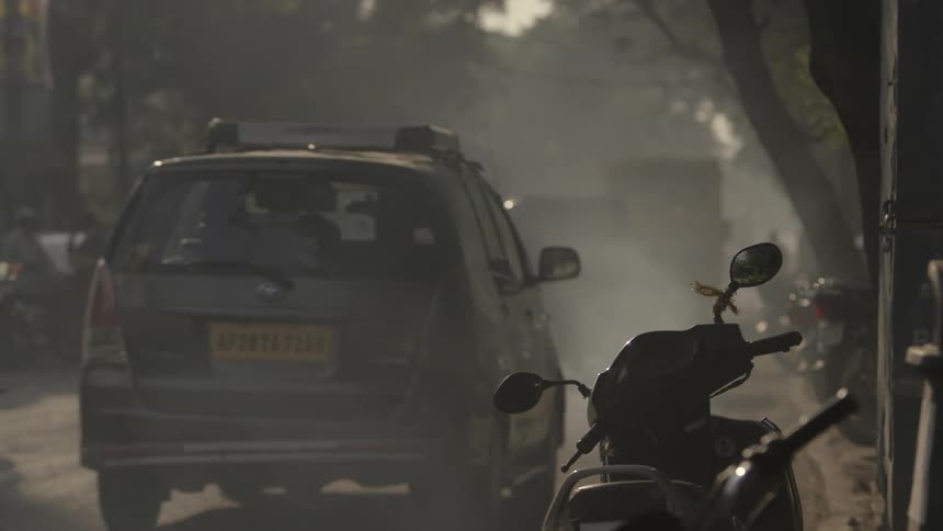 People and cars on a busy road in India