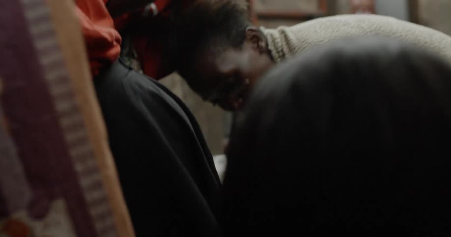 A woman does laundry in a plastic tub as her son walks by