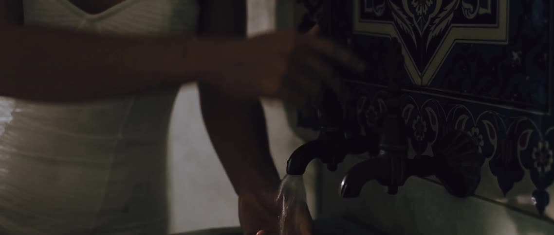 A person washes their hands over a marble sink