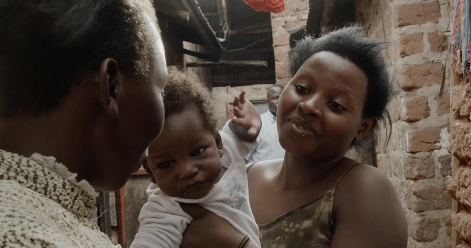 A pair of black women talking as one holds a baby
