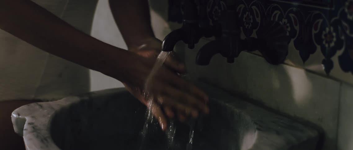 Woman turning on the faucet and washing her hands in a sink
