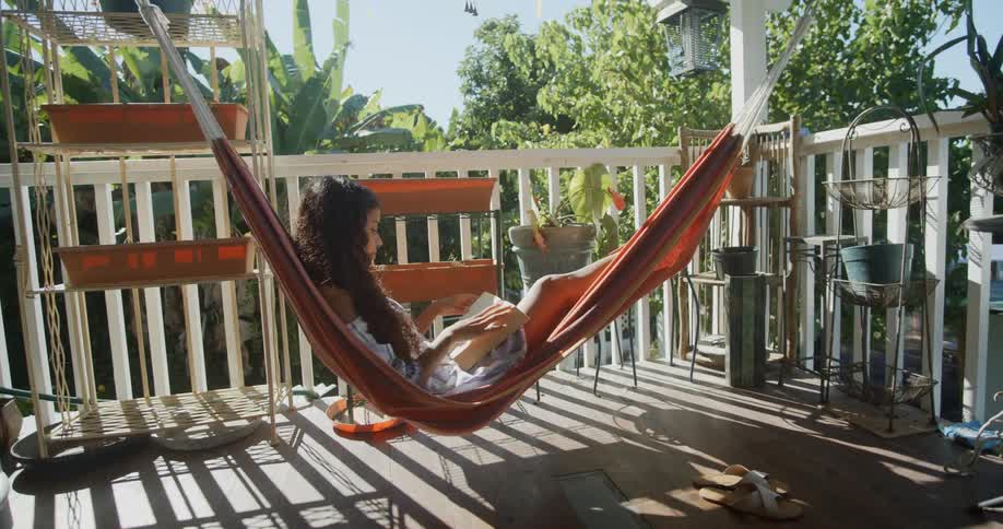 A women reads on a swaying hammock on the deck on a sunny day
