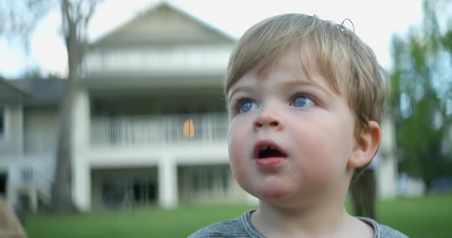 A woman watches a child smiles on the lawn