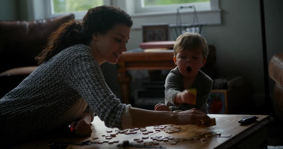 Mother and son playing together with wood pieces on the coffee table