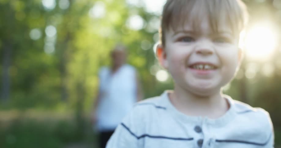 A young boy running towards and pass the camera