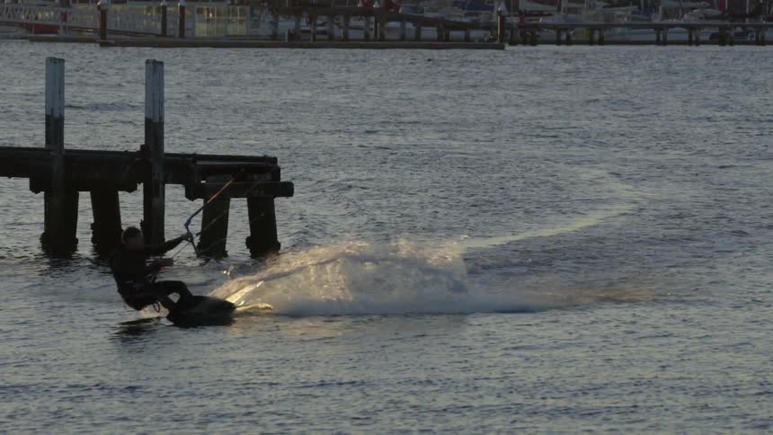 A man is parasailing in the water at sunset