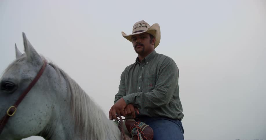 Man in a beige hat rides a white horse