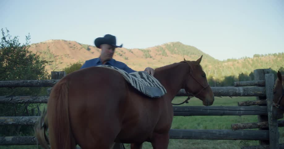 A cowboy saddling a horse
