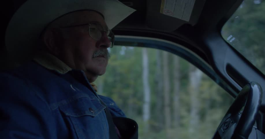 A cowboy in a denim jacket drives a vehicle