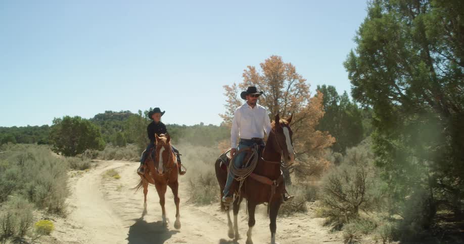A man and his son ride horses down a trail