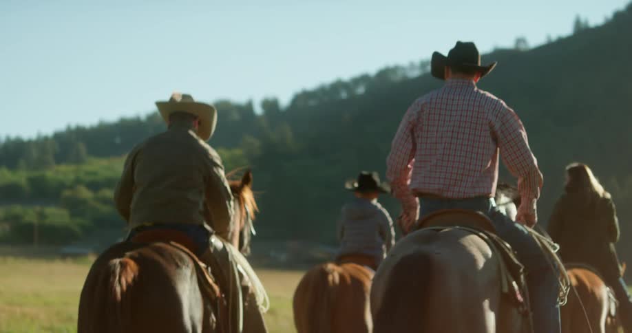A group of cowboys riding horses through a field