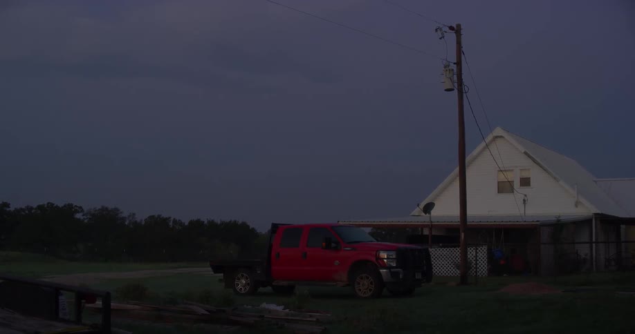 A red pickup truck is parked outside a building in a rural town