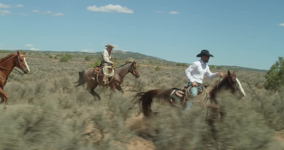 Three men riding horses with the sky in the background
