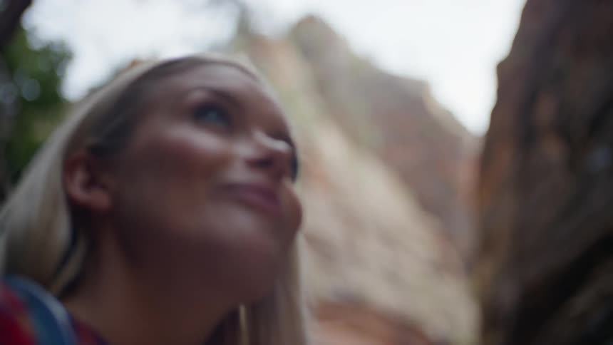A young blonde woman out in nature looks around and smirks