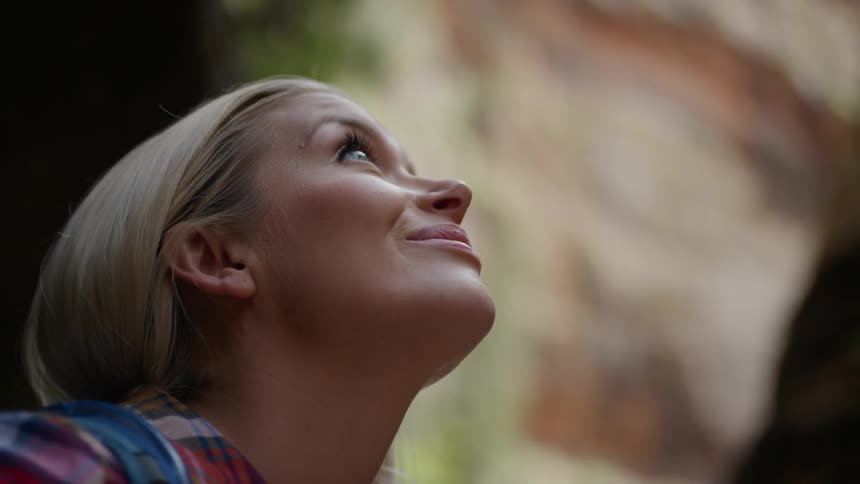 A blonde woman smiles as she looks up cliff