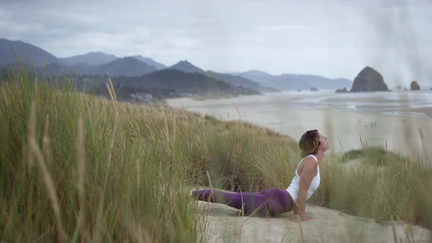 Woman does yoga on the beach among the salt grass
