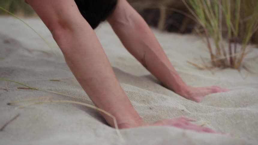 A woman doing yoga outdoors in the sand