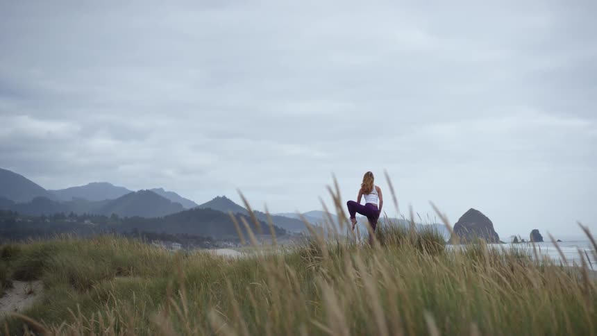 A woman does yoga on a beach