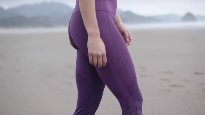 A woman walking barefoot through wet sand on a beach