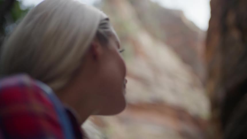 A woman stands at the base of a mountain and looks up in amazement