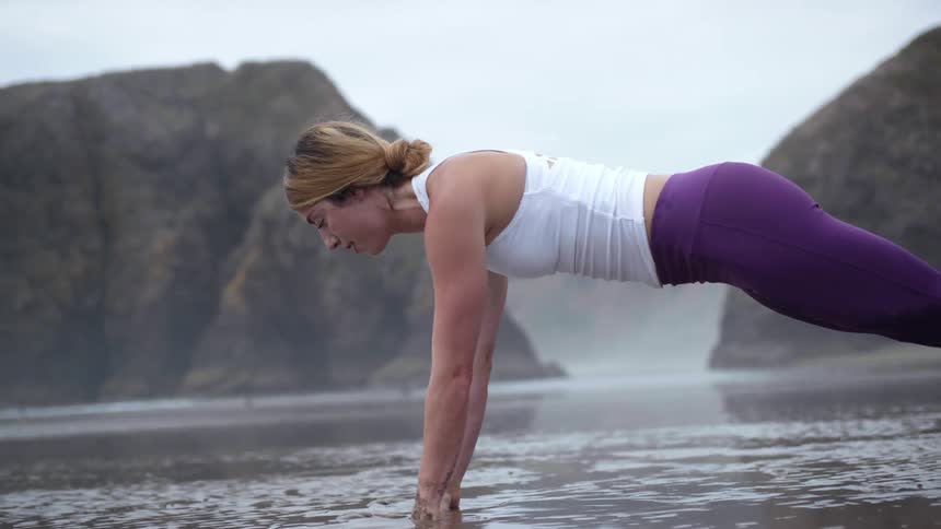 A woman does a plank in the mud