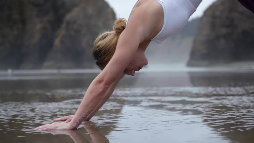 Woman performs yoga on wet sand