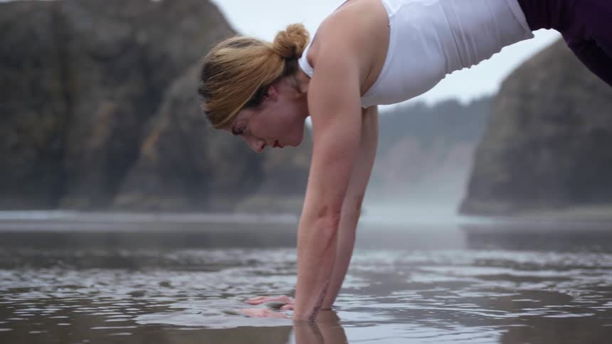 A woman performing stretches on wet sand