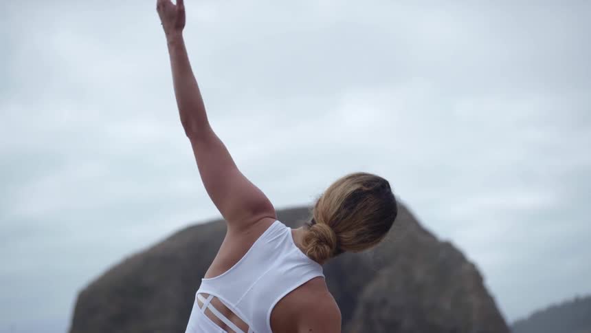 A woman stretches on the rocks