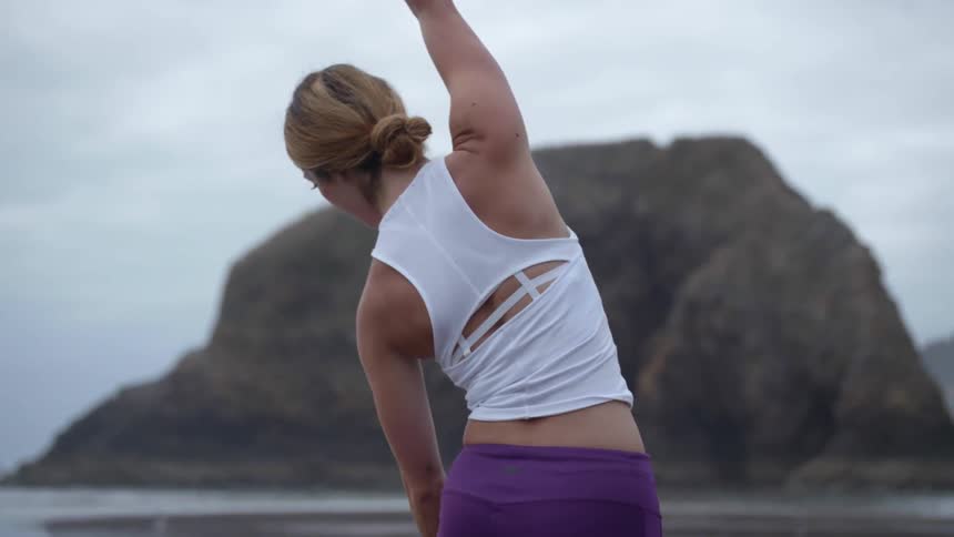 A woman is stretching outdoors my the mountains